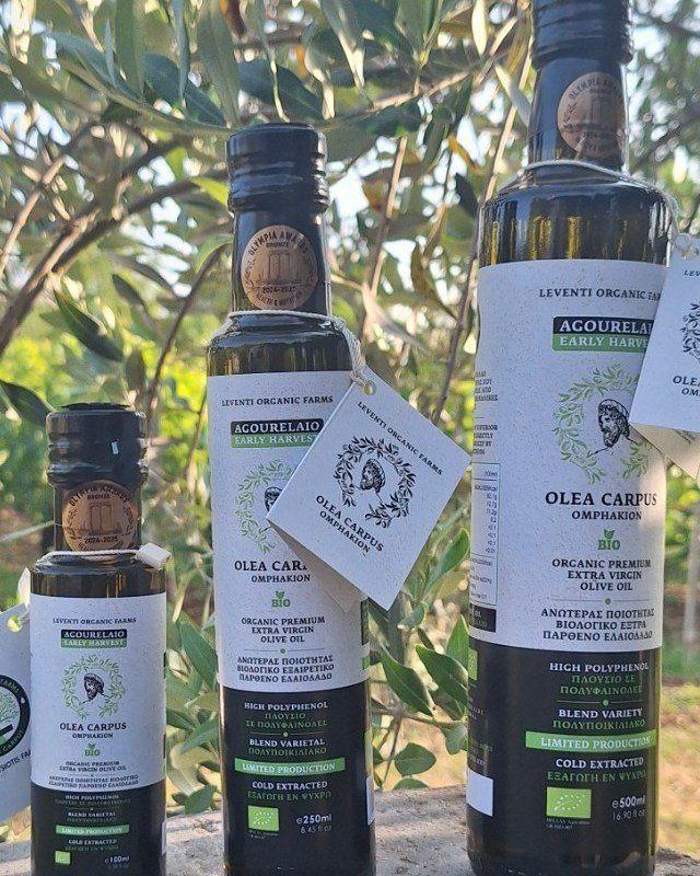 Olea Carpus bottles with olive trees in the outdoor background